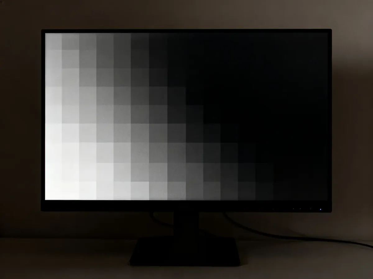 Monitor wyświetlający planszę testową z subtelnymi polami czerni i ciemnych szarości